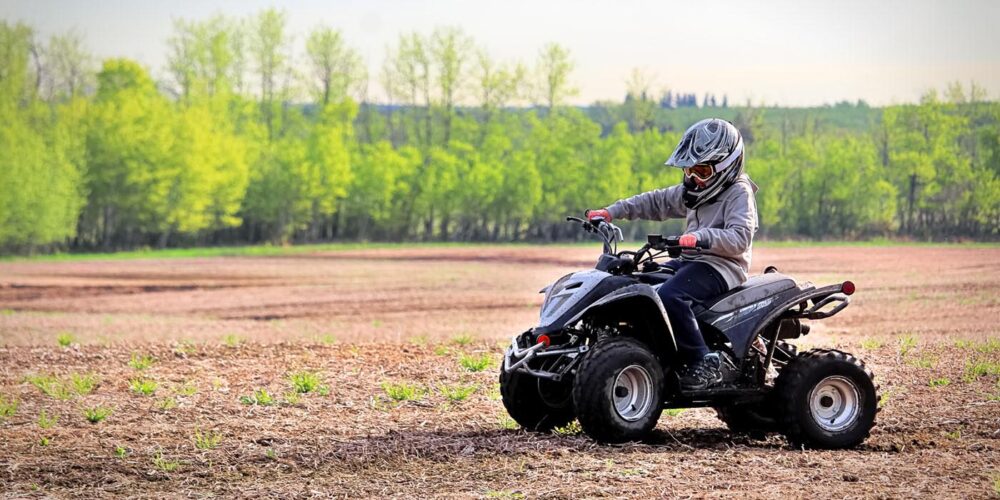 A child riding a youth ATV in a field.
